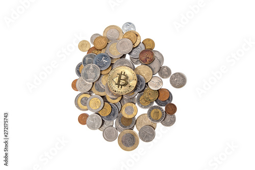 Bitcoin lying on top of a pile of coins from different countries on a white isolated background