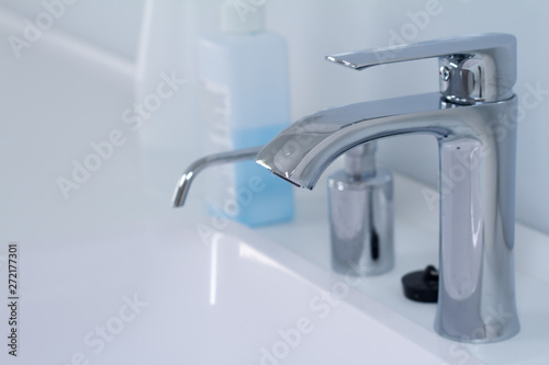 A modern water tap sink with faucet in minimalistic style and built-in soap dispenser in expensive loft bathroom  soft focus