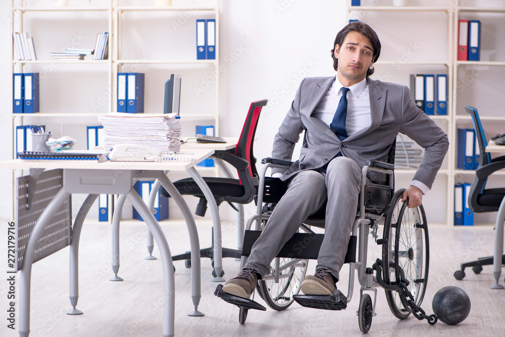 Young handsome employee in wheelchair working in the office Young handsome employee in wheelchair working in the office