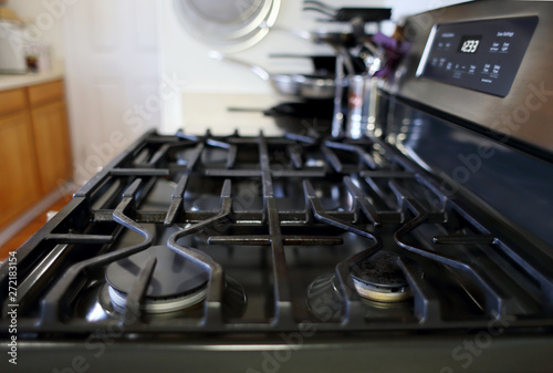 Empty natural gas stove top with cast iron grates, inside a home kitchen.