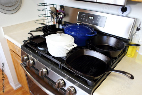 Collection of cast iron cookware on the stove top in a home kitchen.