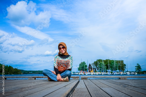 A muslim woman with hijab pose on a wooden dock in Canada © Aqnus