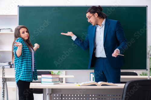 Young handsome teacher and female student in the classroom 