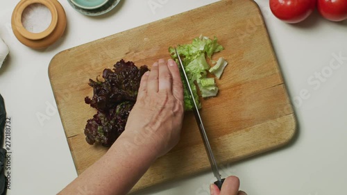 Hands cutting a lettuce on a wooden board