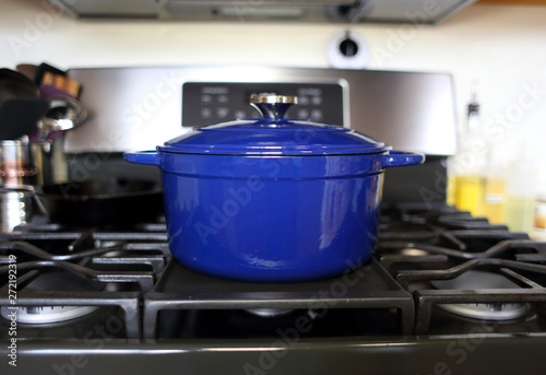 Blue 6 quart Dutch oven resting on a modern natural gas stove.