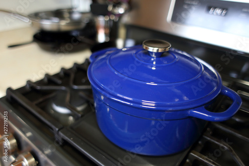 Blue 6 quart Dutch oven resting on a modern natural gas stove.