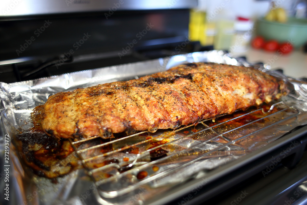 Rack of St. Louis cut style ribs resting in a baking tray on the stove top.