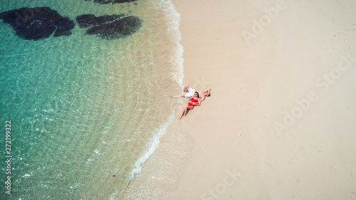 Beach drone view Phuket tropical island, white beach with waves, couple lying on the beach. Aerial Photo.