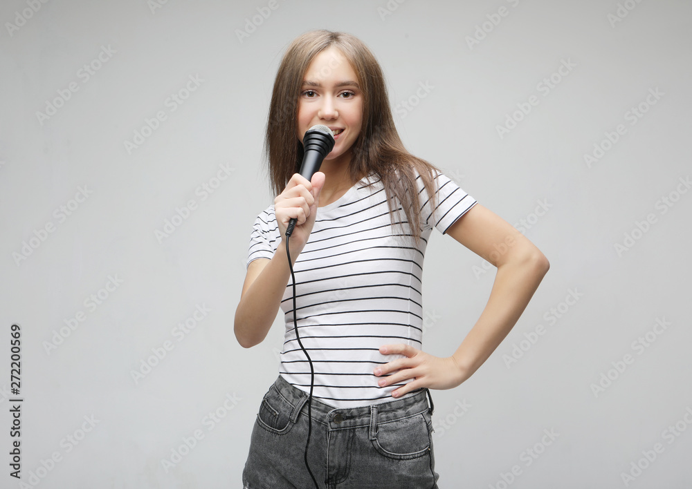 Beauty model girl singer with a microphone over light grey background Beauty model girl singer with a microphone over light grey background