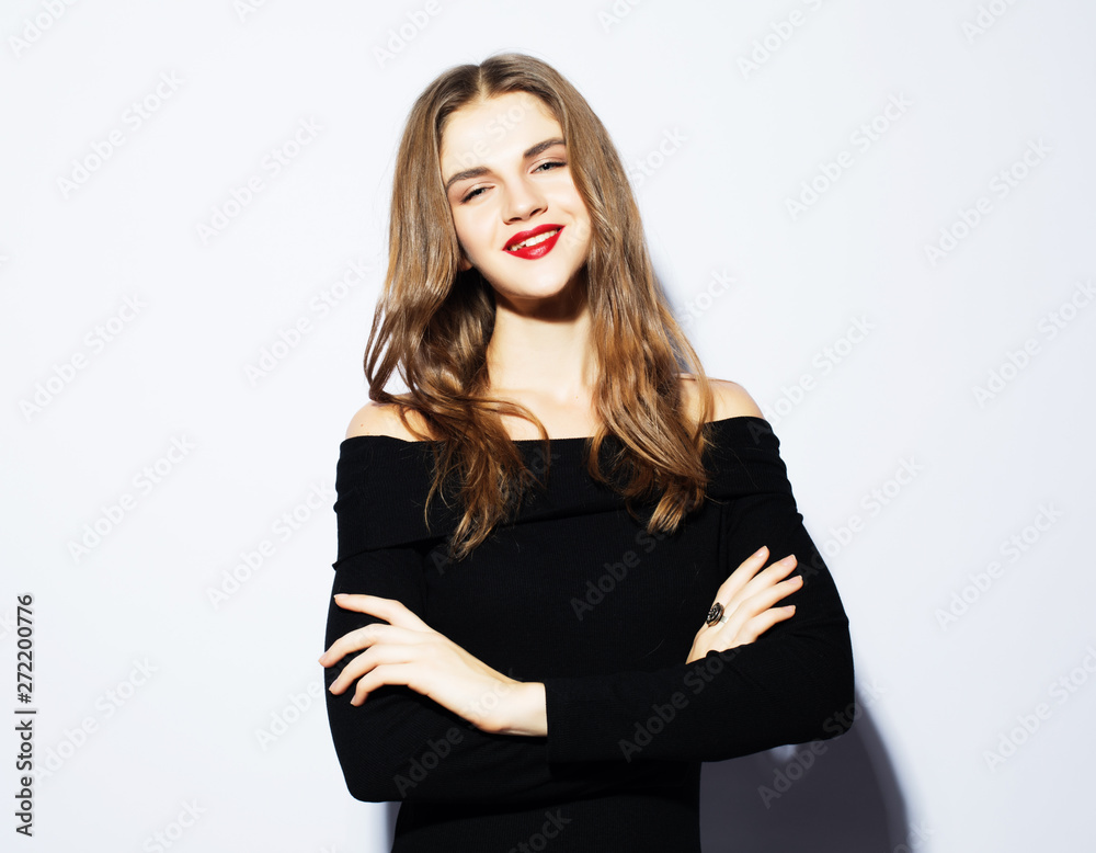 Young beautiful blond woman wearing black dress posing over white background