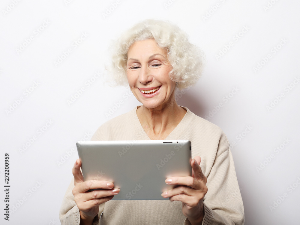 lifestyle, technology and people concept: Happy mature woman using a tablet lifestyle, technology and people concept: Happy mature woman using a tablet