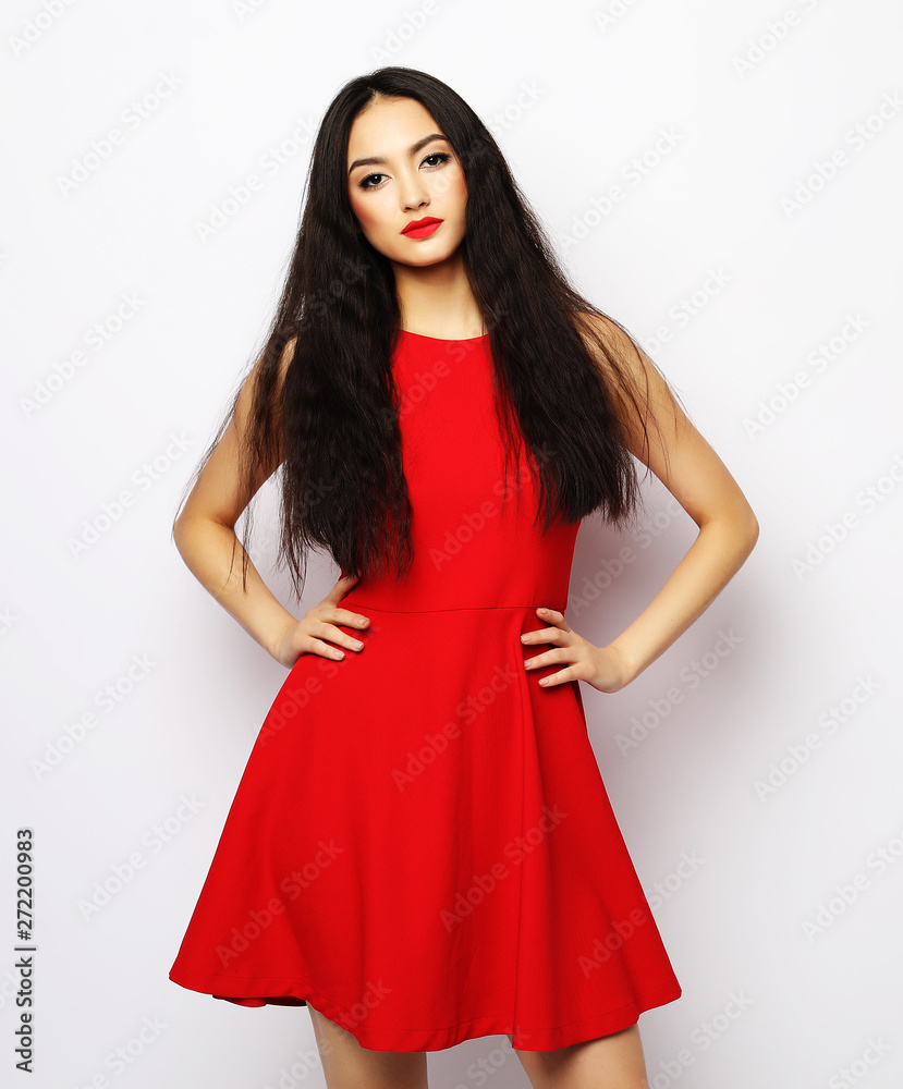 Young beautiful woman wearing red dress posing over white background