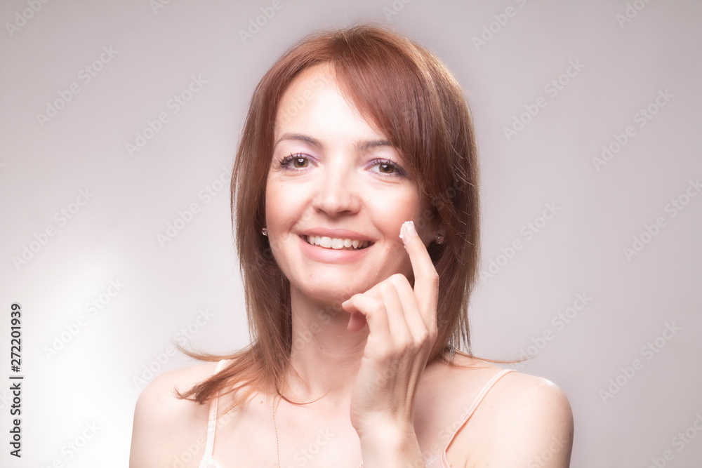 one mature woman, applying skin cream to her face.