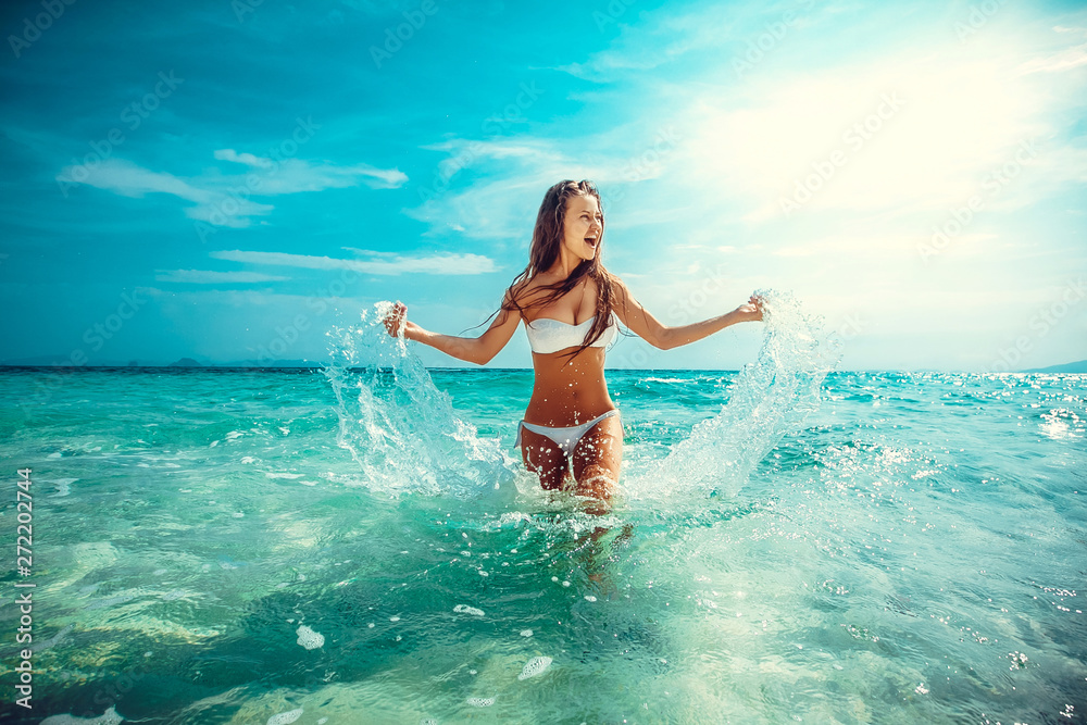 Beautiful emotional Model Girl making splash in the sea and laughing. Beautiful Woman Hot Girl enjoying the Waves of the Ocean. Tropical vacation