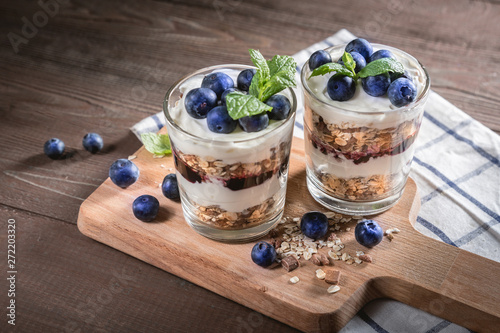 Yogurt with granola and fresh blueberries on rustic background