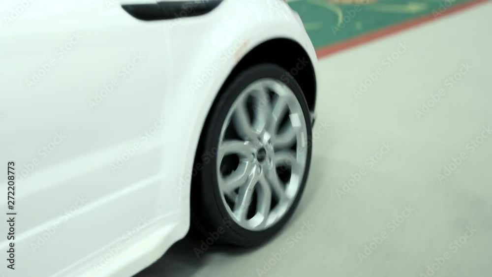 Close up kid driving mini car in amusement park. Detail of white toy car in motion. Kids entertainment center. Close up kid driving mini car in amusement park. Detail of white toy car in motion. Kids entertainment center.