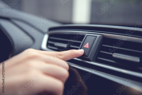 Finger hitting emergency light stop botton in the car , man pressing red triangle car hazard warning button. © oatawa