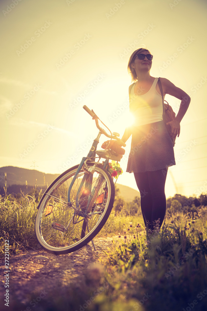 Enjoying the evening sun, sundown scenery: woman with bike is standing  beside her bike, sunbeam Stock Photo | Adobe Stock
