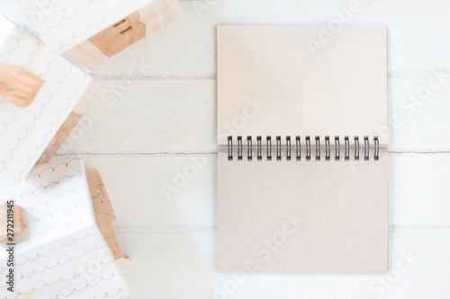 Blank paper notebook with Miniature house model on white wood background