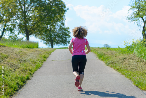 Fit muscular woman running on a rural road