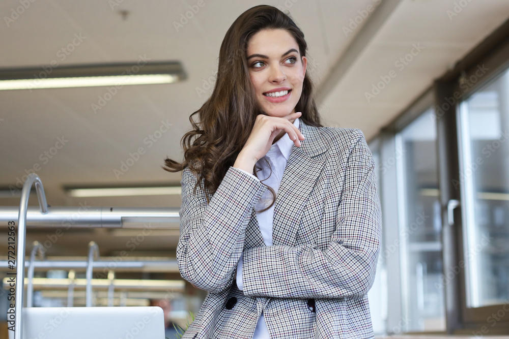 Attractive businesswoman standing near desk in the office.