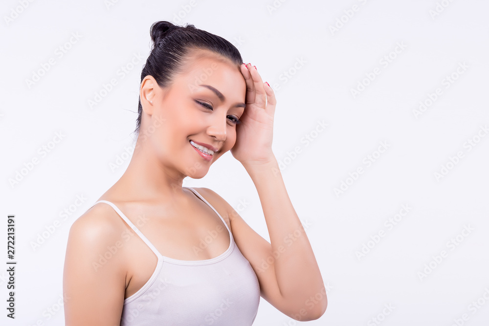 Asian girl with healthy skin wearing a white singlet standing isolated over white wall background. With a smile Her eyes closed and hands touching the face expression of beautiful skin with copy space Asian girl with healthy skin wearing a white singlet standing isolated over white wall background. With a smile Her eyes closed and hands touching the face expression of beautiful skin with copy space