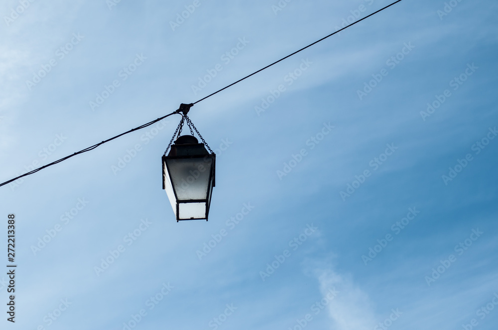 Closeup of vintage street lamp on cable on blue sky background