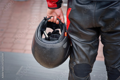Foto Biker in leather panths hold in hand black motorcycle helmet
