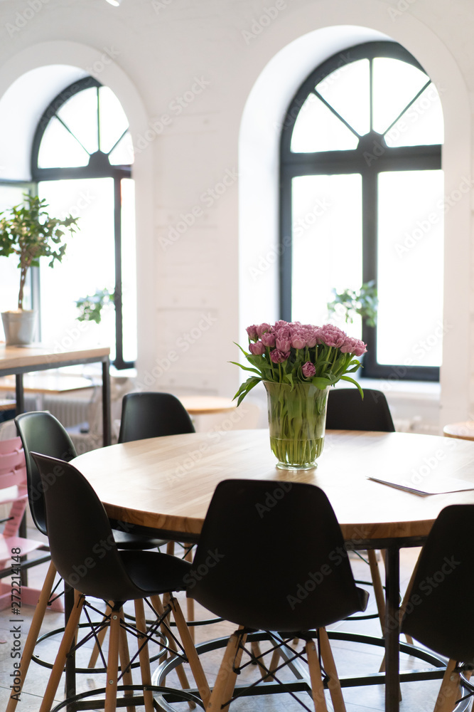 Modern fashionable cafe restaurant, spacious bright space of the bakery and desserts. The sun in the windows, the flowers on the table.