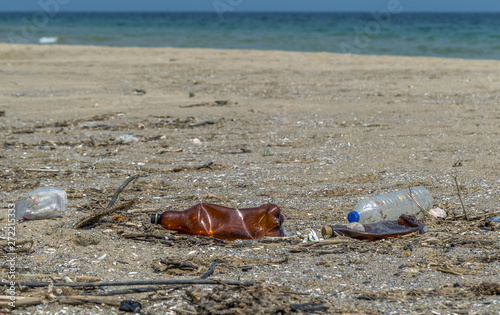 Conceptual: Disaster, Environmental problem - plastic trash. Spilled garbage on the beach of big city. Empty used dirty plastic bottles. Dirty sea, sandy coast of Black Sea. Environmental pollution