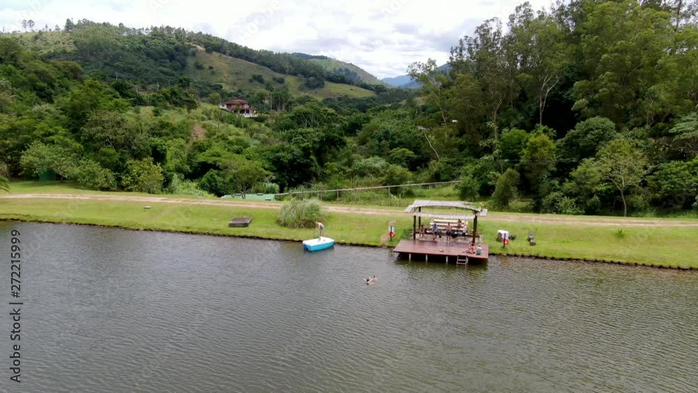Aerial view of beautiful little wood cabana next the lake in tropical mountain, with family enjoying relax sun moment, swimming and fishing. Monte Alegre Do Sul, Brazil. Aerial view of beautiful little wood cabana next the lake in tropical mountain, with family enjoying relax sun moment, swimming and fishing. Monte Alegre Do Sul, Brazil.