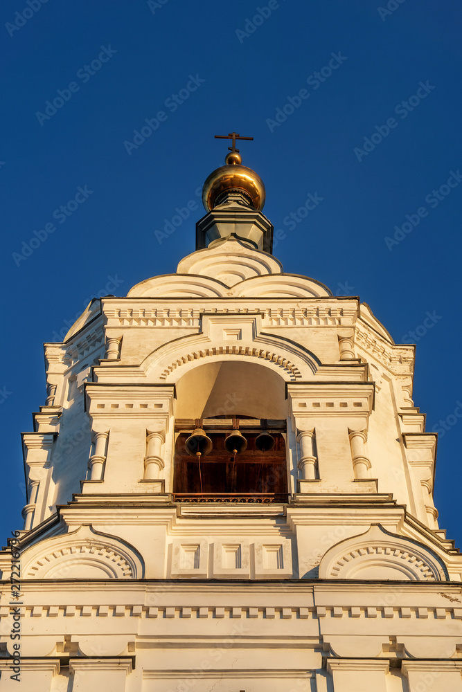 Closeup of the bell tower of the Holy Trinity Stephan monastery. The setting sun emphasizes the decoration of the building. The bells of the belfry are visible.