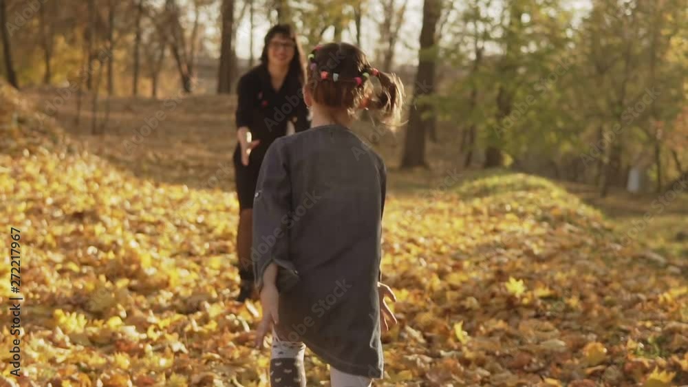 Mother circling in hands her daughter. Family having fun outdoor in slow motion. Daughter running to mom in autumn park. Happy family concept. Medium shot. Mother circling in hands her daughter. Family having fun outdoor in slow motion. Daughter running to mom in autumn park. Happy family concept. Medium shot.