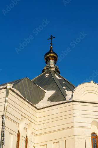 Close-up of one of the buildings of the Perm Holy Trinity Stefanov monastery on the background of the monastery garden. Narrow high Windows, decorated walls and gilded dome. Winter. On the roof snow. photo