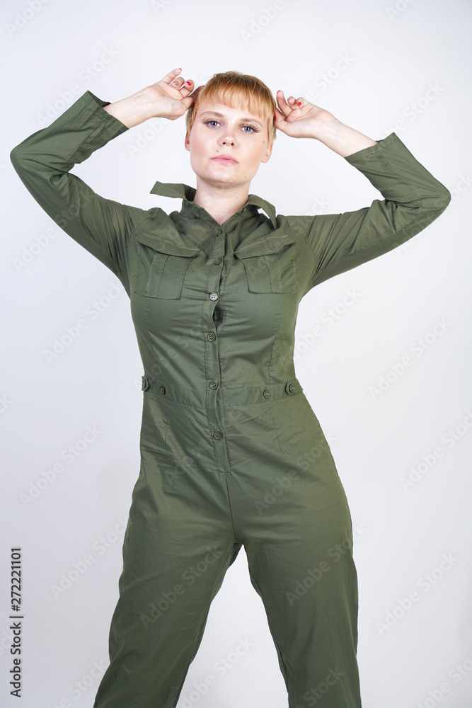 fashionable young woman with short hair in stylish city jumpsuit on white background in Studio. trendy girl in bright overall standing and posing alone. fashionable young woman with short hair in stylish city jumpsuit on white background in Studio. trendy girl in bright overall standing and posing alone.