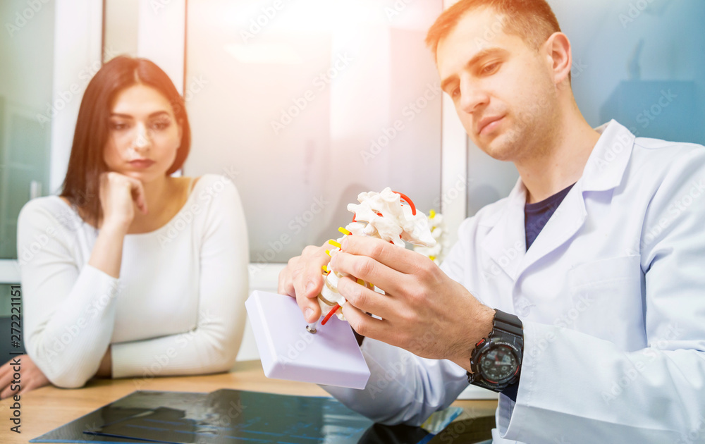 Orthopedist showing spine model to patient in hospital Orthopedist showing spine model to patient in hospital