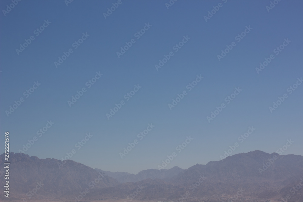 abstract nature wallpaper pattern photography of mountain silhouette in morning slightly foggy weather time with empty blue sky background and empty space for copy or text