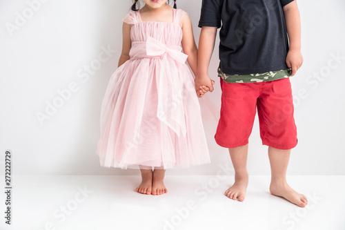 白背景に子供の男の子とドレスを着た女の子が手を繋いでいる