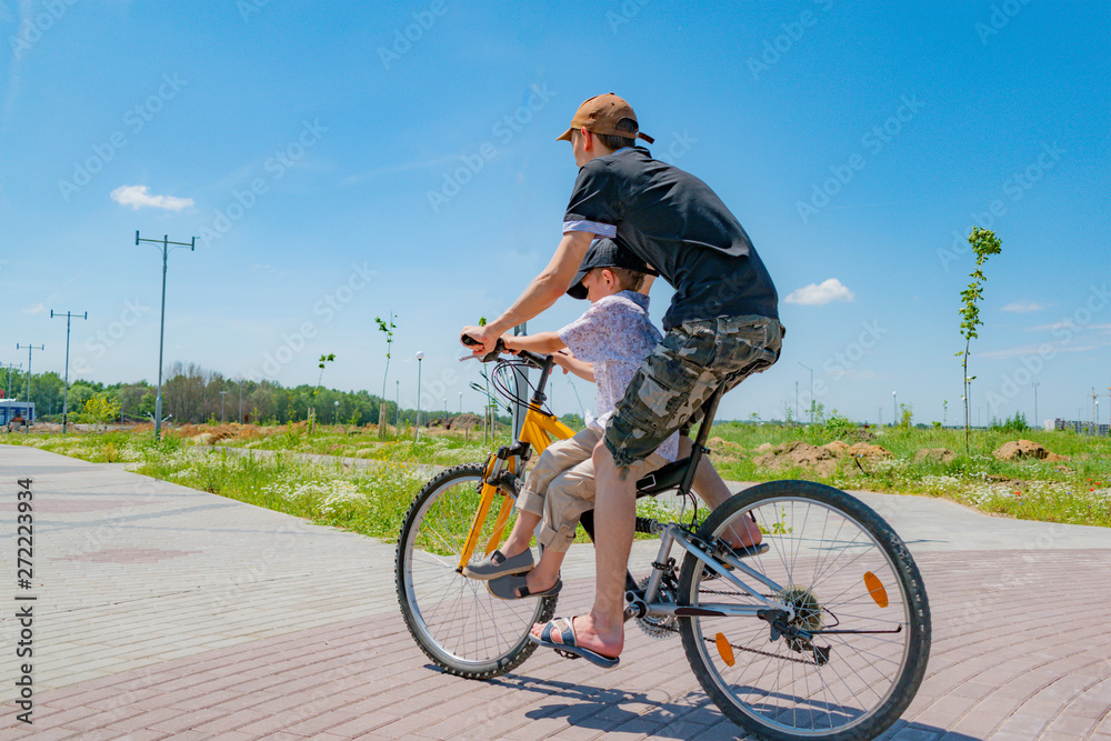 Obraz premium Older and younger brothers ride a bike