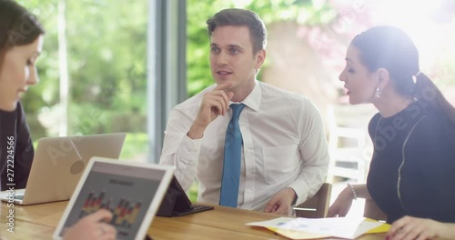 4K Happy young business team looking at sales figures on computer & discussing. Slow motion.