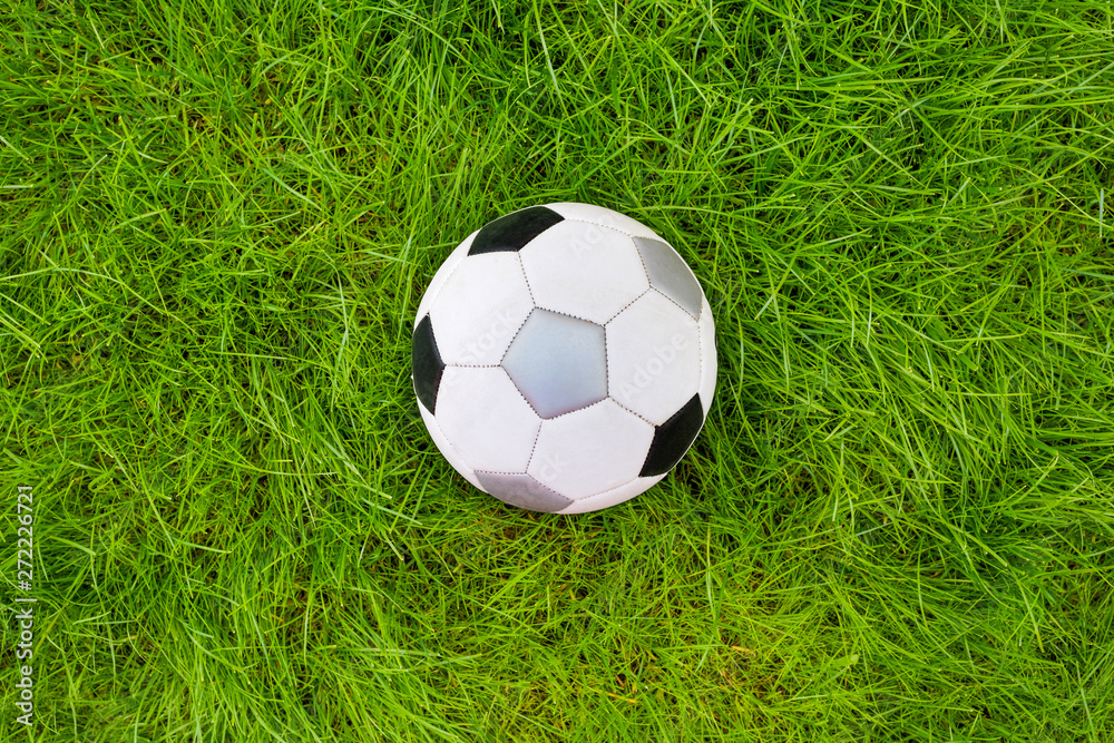 Obraz premium A football ball on green grass. A view from above.