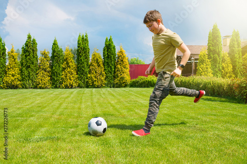 An 11-year old teenager is playing football in the house backyard. Sport lifestyle.