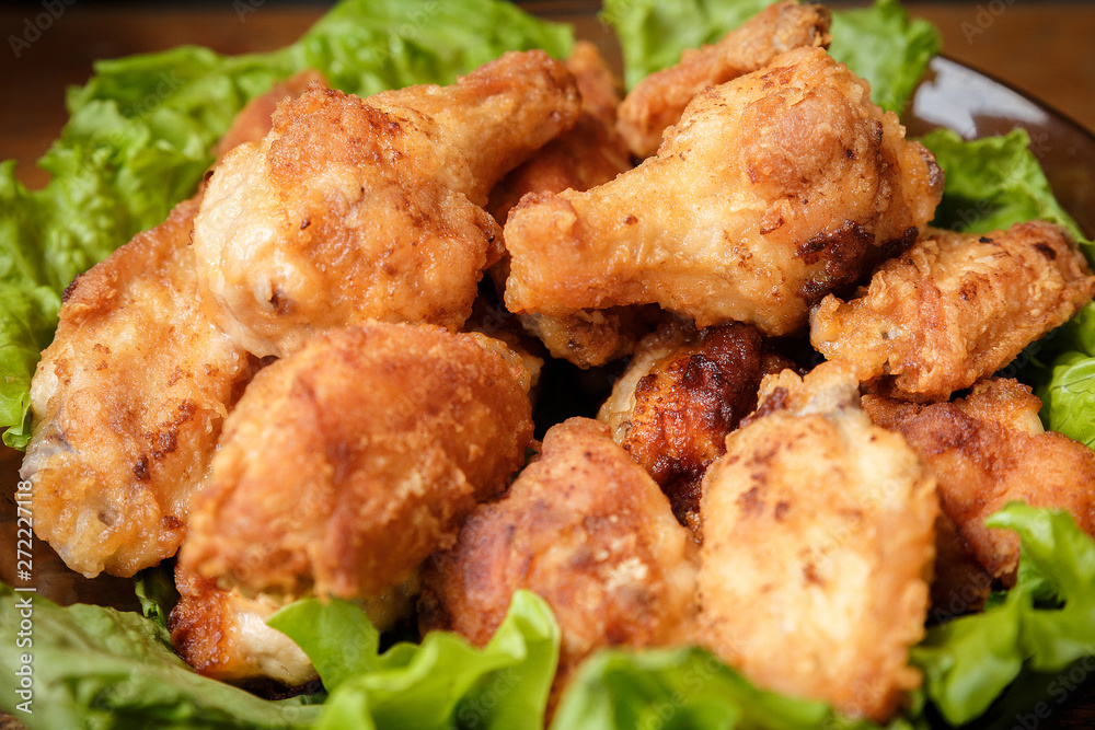 Fried chicken shins in a crispy crust on lettuce leaves in a plate.