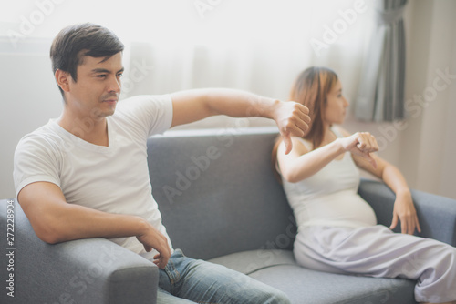 Young angry man and woman are sitting on sofa at family's home. To be new Mother and Father, pregnant woman concept.
