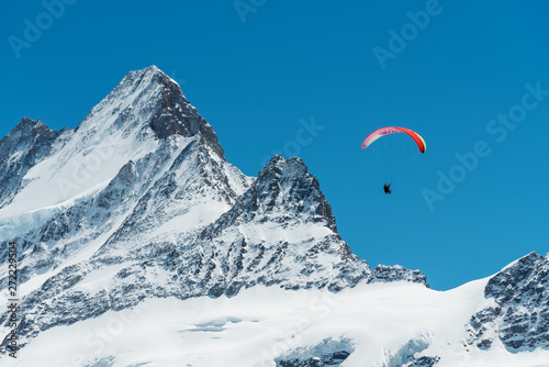 Alps mountains full of snow with blue sky and paragliding on the air in summer at Switzerland