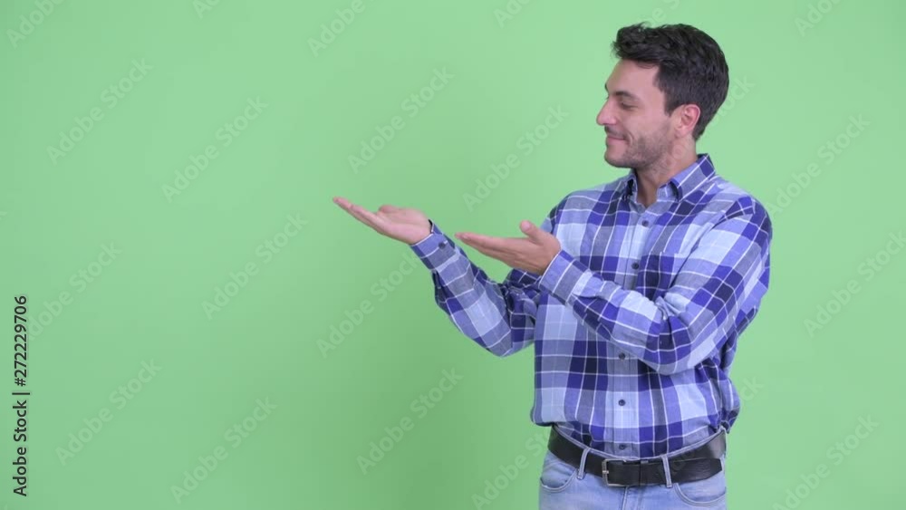 Happy young handsome Hispanic man showing something Happy young handsome Hispanic man showing something