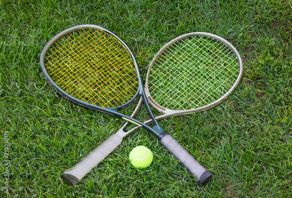 Wimbledon sign, two tennis rackets with a ball on grass