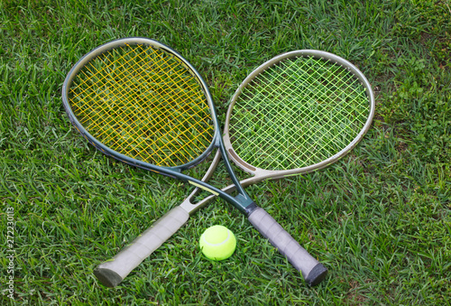 Wimbledon sign, two tennis rackets with a ball on grass