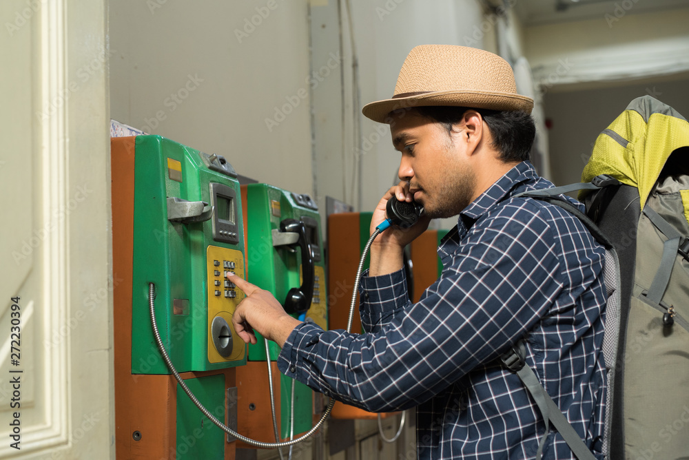 Fototapeta premium Young traveler using public payphone
