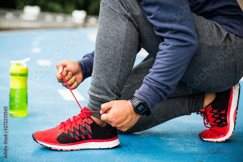 Athlete male hands tying shoelace on running shoes